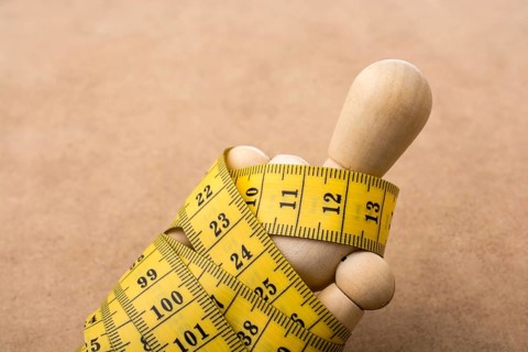 Yellow color measuring tape wrapped on wooden man