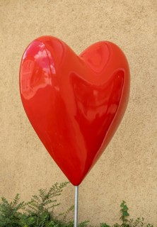 Red plastic heart in front of a house