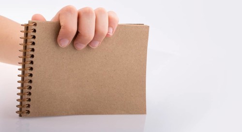 Hand holding brown color notebook on a white background