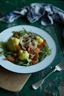 Vegan cauliflower salad on a tin plate with black cumin on a rustic table