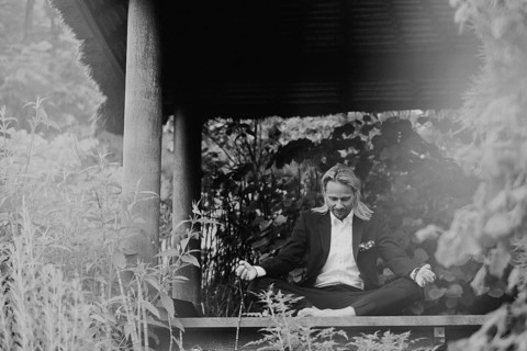 Businessman does yoga on wooden walkway in nature,