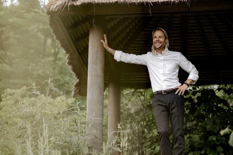 Businessman in a white shirt stands on the wooden jetty in the greenery,