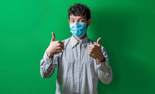Isolated man with mask on giving thumbs up, Person giving thumbs up with mask on isolated. Concept of the correct use of the surgical mask