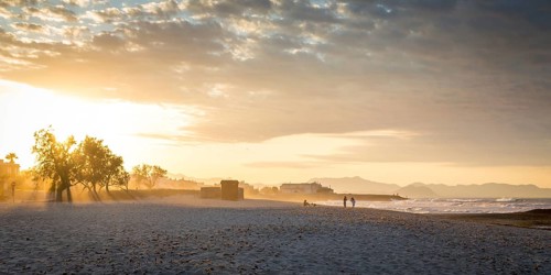 Evening atmosphere at the sandy beach playa in Son Serra de Marina, Tramuntana Mountains in the back