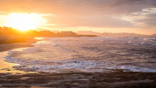 Sunset at the sandy beach playa in Son Serra de Marina, Tramuntana Mountains in the back
