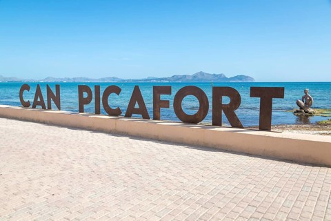 Beach promenade with Can Picafort lettering, sculpture by Joan Bennassar in the back