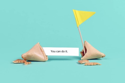 Fortune cookie with motivational text saying 'You can do it' with flag on real blue background,