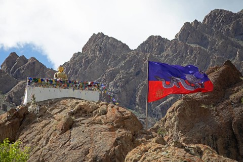 Maitreya Buddha and traditional Tibetan dragon flag, Hemis Gompa