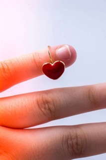 Red color heart shape earring in hand on white,