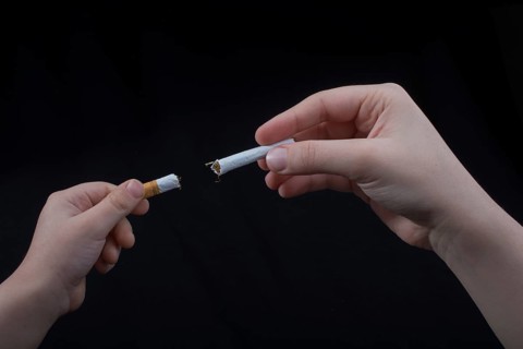 Hand is breaking a cigarette on a black background,