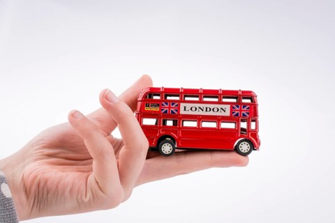 Hand holding a London double decker bus on a white background,