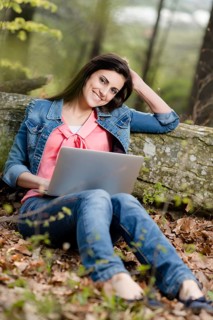 Young woman sitting in the forest with laptop,