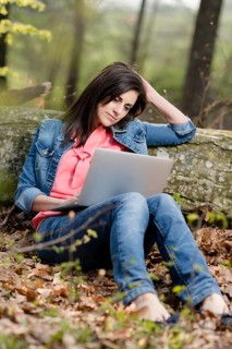 Young woman sitting in the forest with laptop,