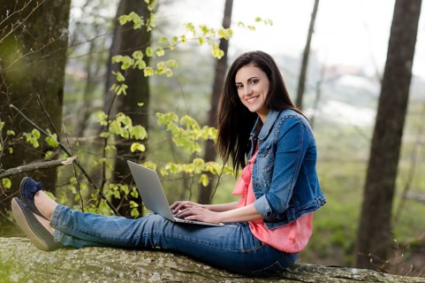 Young woman sitting in the forest with laptop,