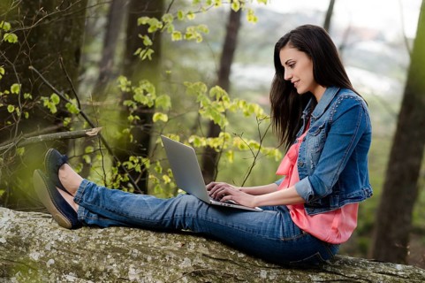 Young woman sitting in the forest with laptop,