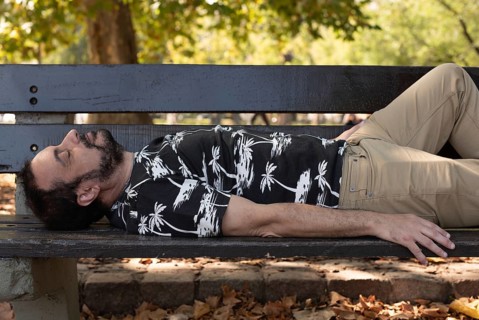 A man sleeping on a bench at the park,