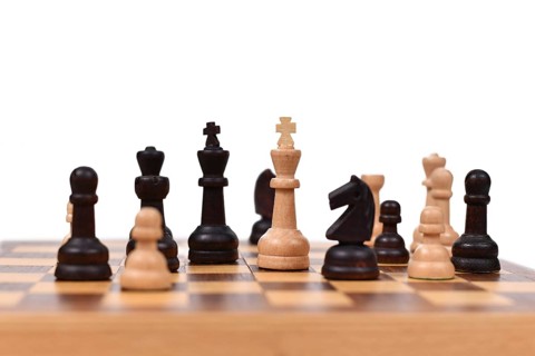 Chess board game with focus on white queen pieces on white background,