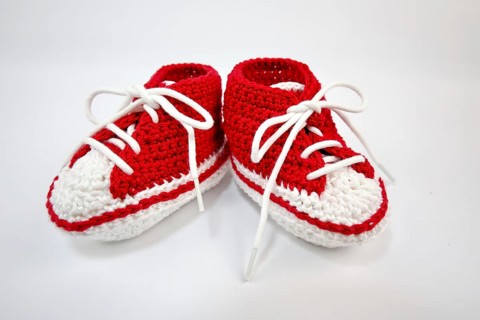 Baby shoes or crochet shoes in red and white isolated against a white background,