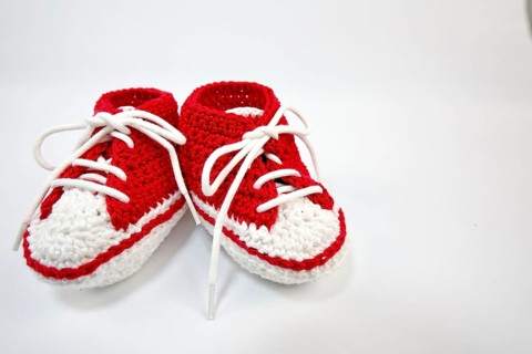 Baby shoes or crochet shoes in red and white isolated against a white background,