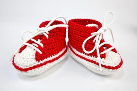 Baby shoes or crochet shoes in red and white isolated against a white background,