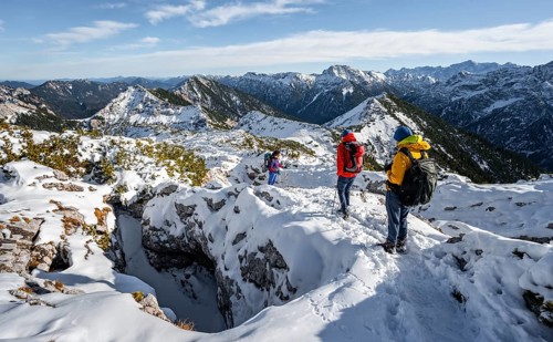 Three mountaineers between snowy karst rocks, hiking to Ammergauer Hochplatte