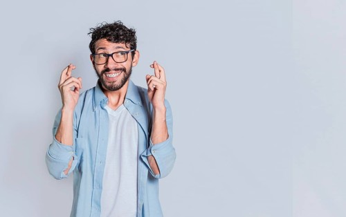 Concept of positive person making a wish and crossing his fingers on isolated background. Positive people smiling making a wish while crossing his fingers. Happy man making a wish crossing his fingers...