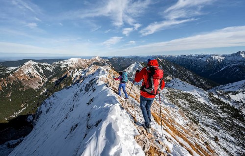 Two mountaineers on the rocky snowy ridge of the Ammergauer Hochplatte, view towards Loesertaljoch