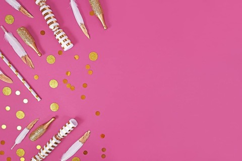 Party flat lay with golden and white decoration like confetti and feathers on pink background with copy space,