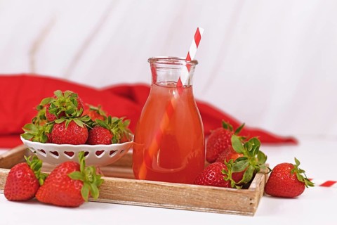 Jar with strawberry fruit lemonade surrounded by berries,