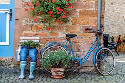 Curious decoration on a front door, blue jeans trousers in rubber boots with flower pot