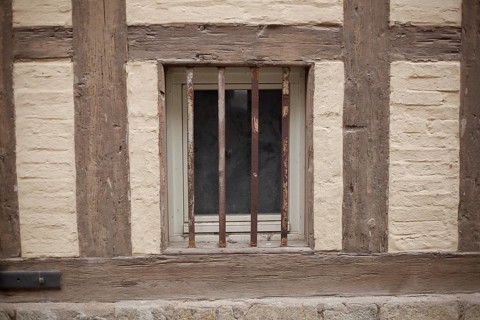 Old window with window grille on a brown house wall with half-timbered beams, Quedlinburg