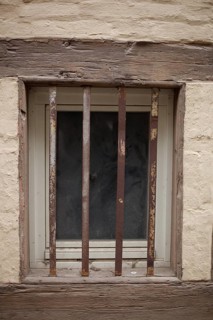 Old window with window grille on a brown house wall with half-timbered beams, Quedlinburg