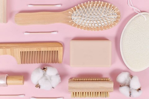 Eco friendly wooden beauty and hygiene products like comb and soap on pink background,