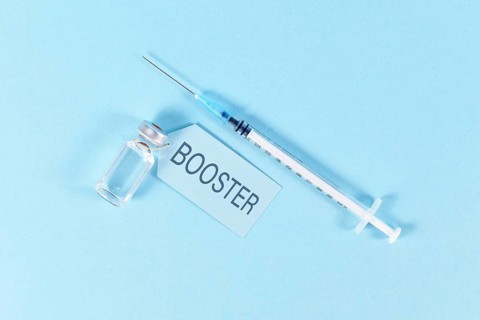 Concept for Corona virus booster vaccination with vial and syringe on blue background,