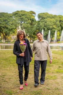 Mature transgender woman walking hand in hand with her boyfriend in a park happy because he gave her flowers,