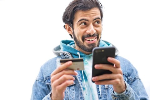 Latin man using credit card to make online payment on smartphone. mixed-race man using cellphone for shopping online. Guy using smart phone to check credit card transactions from app. White background...