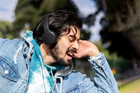 Young latin man listening to music outdoors with headphones. Expression of happiness, winning attitude