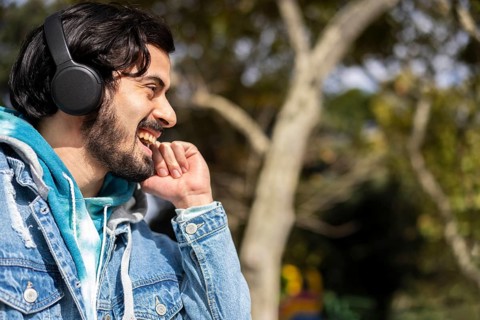 Young latin man listening to music outdoors with headphones. Expression of happiness, winning attitude