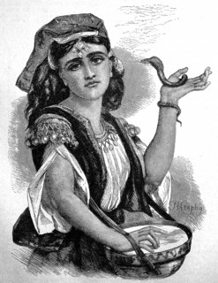 Snake tamer in Cyprus, young woman with a small snake and a drum at a performance