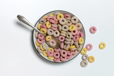 Fruit-flavoured cereal rings in bowl and spoon, children's breakfast