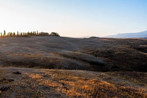 Country house with cypress avenue on a hill, first morning sun