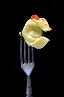 A tortelloni with tomato sauce on a fork, pasta