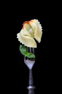 A tortelloni with tomato sauce on a fork, pasta