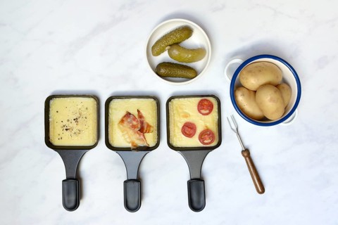 Raclette, melted raclette cheese in pans and ingredients