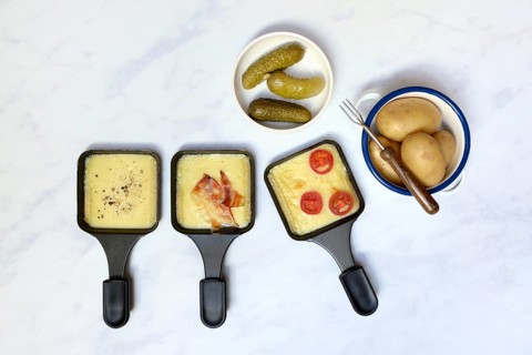 Raclette, melted raclette cheese in pans and ingredients