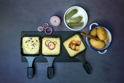 Raclette, melted raclette cheese in pans and ingredients