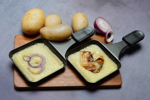 Raclette, melted raclette cheese in pans and ingredients