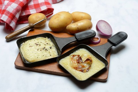 Raclette, melted raclette cheese in pans and ingredients
