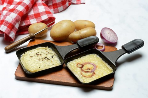 Raclette, melted raclette cheese in pans and ingredients