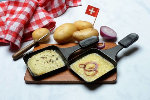 Raclette, melted raclette cheese in pans and ingredients